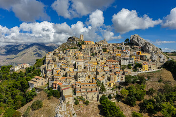 Fototapeta premium Aerial drone view of Sclafani Bagni, a small historic Sicilian mountain town perched on cliffs with panoramic views of Caltavuturo and rugged Madonie Mountains, Sicily, Italy.Small Village in Sicily