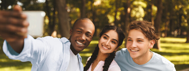 Capturing moments. Cheerful african american student guy taking selfie with his university friends,...