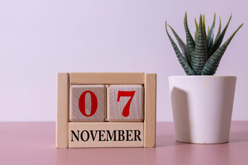 November 6 on a wooden calendar next to an alarm clock on a dark table.