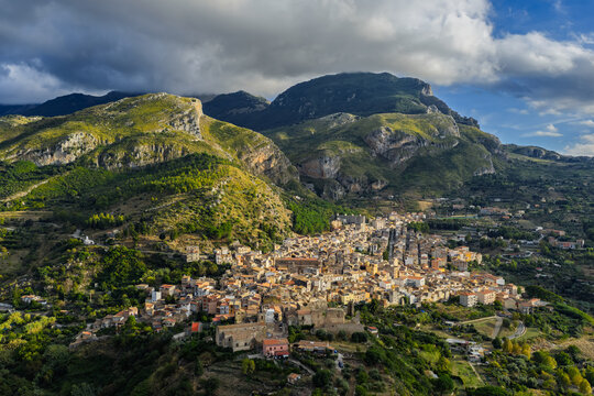 Aerial drone view of Collesano Sicilian mountain town at sunset with Basilica San Pietro church and historic stone streets in the Madonie Mountains, Sicily, Italy. Old mountain town in Sicily
