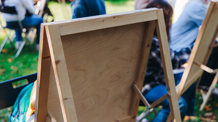 Kids drawing at plein air, group class of talented children with painting easel and wooden canvas during lesson of watercolor painting outdoors in summer, art school class for young teen artists