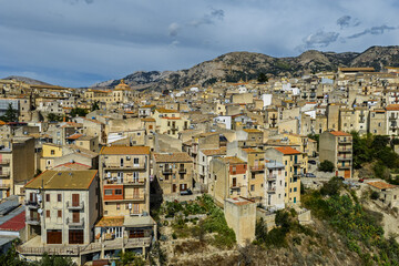 Aerial drone view of Polizzi Generosa, a picturesque Sicilian mountain town perched on rocky cliffs showcasing traditional stone buildings and panoramic views of the Madonie Mountains, Sicily, Italy