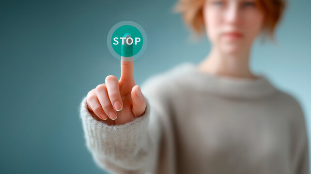 A woman touches a transparent virtual interface with her finger and presses a bright button with the word &ldquo;STOP.&rdquo; The background is slightly out of focus.