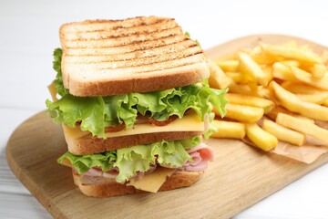 Tasty sandwich served with french fries on white wooden table, closeup
