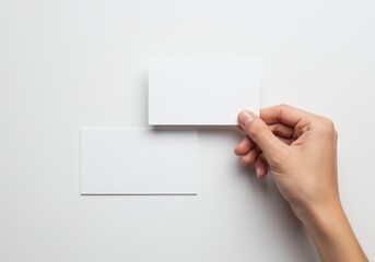 Fototapeta premium Hand holds blank white card over another for presentation.