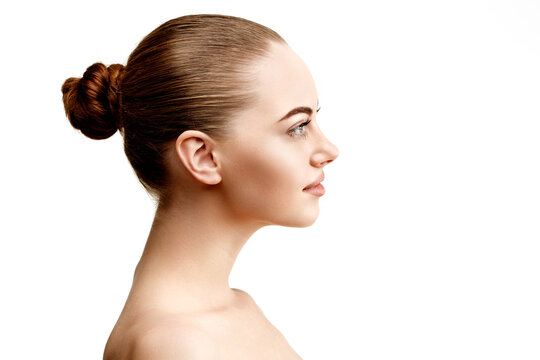 Side profile of a young woman with smooth skin and elegant bun hairstyle on white background. Minimal beauty concept showing natural elegance, wellness, and skincare perfection.