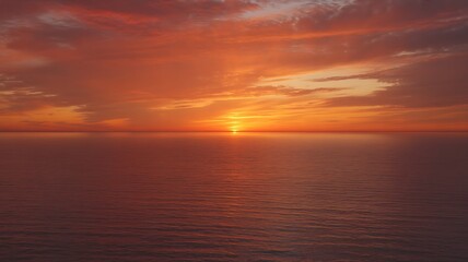 Naklejka premium Dramatic sunset over a calm ocean with vibrant orange and red clouds water