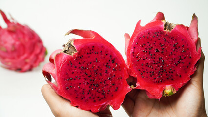 Fresh red dragon fruit pieces that have been cut are placed on a hand isolated on a white...