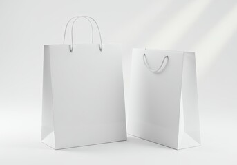 Two plain white shopping bags with rope handles stand on a white surface.