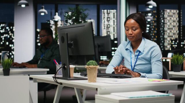 Businesswoman focused on proofreading and planning project data for objectives achievement, solving tasks late at night in the dark office. Executive insight focused on budgeting and targets. Camera B