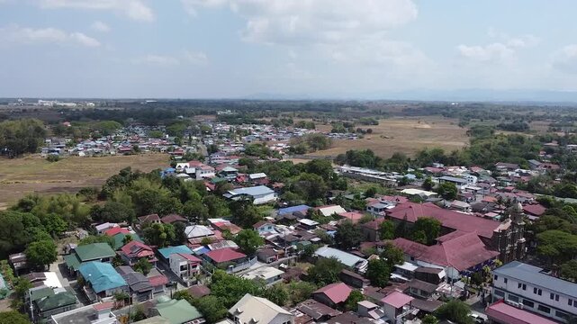 Aerial Drone Shot Moving Backward over a Lakeside Community in Malolos, Bulacan, Philippines with Green Trees and Colorful Houses under a Clear Sky