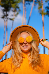 Woman faceless yellow sweater closing eyes with orange dahlia into camera Autumn Fall Bouquet for Thanksgiving holiday. Seasonal Warm colorful blossom flowers arrangement festive decoration. Selective