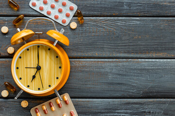 Medical treatment pills and vintage alarm clock, top view. Time to take medicine concept