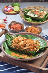 Grilled rice with shredded chicken and spiced grated coconut, wrapped in banana leaves, a traditional Indonesian dish