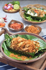 Grilled rice with shredded chicken and spiced grated coconut, wrapped in banana leaves, a traditional Indonesian dish