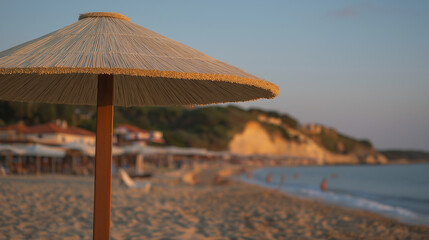 Sunny beach with gentle waves and a single umbrella under warm golden hour light.