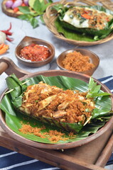 Grilled rice with shredded chicken and spiced grated coconut, wrapped in banana leaves, a traditional Indonesian dish