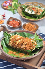 Grilled rice with shredded chicken and spiced grated coconut, wrapped in banana leaves, a traditional Indonesian dish