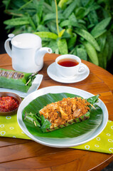 Grilled rice with shredded chicken and spiced grated coconut, wrapped in banana leaves, a traditional Indonesian dish