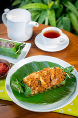 Grilled rice with shredded chicken and spiced grated coconut, wrapped in banana leaves, a traditional Indonesian dish