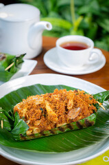 Grilled rice with shredded chicken and spiced grated coconut, wrapped in banana leaves, a traditional Indonesian dish