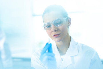 A researcher examines a newly engineered synthetic organism that glows as a biological sensor, or a quantum dot nanoparticle assay for instantaneous and highly sensitive disease detection.