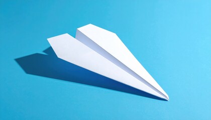 A sleek white paper airplane rests on a vibrant blue background, showcasing its aerodynamic design