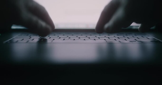 Silhouette of Man Typing on Laptop at Night