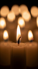 A single burning candle flame glowing in the dark. Close-up of candlelight for a memorial vigil. All Souls' Day remembrance concept