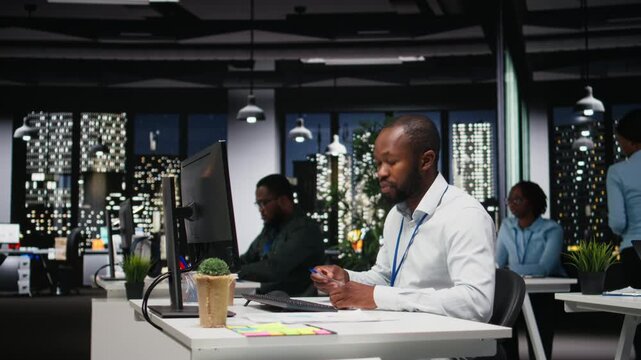 African american employee writing growth strategy notes on a textbook, working at night with insights and financial data. Consultant ensuring operational success and efficiency. Camera A.
