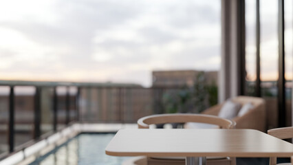 Wooden table and chair aside outdoor high rise swimming pool with glass partition and panoramic view