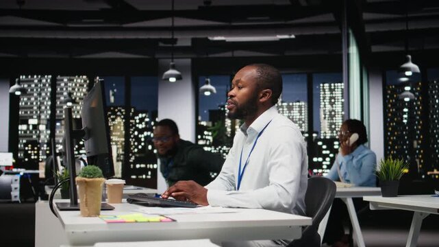 African american staff members consulting each other for monthly reports, reviewing KPI data insights for business productivity late at night. Collaboration between employees for success. Camera A.