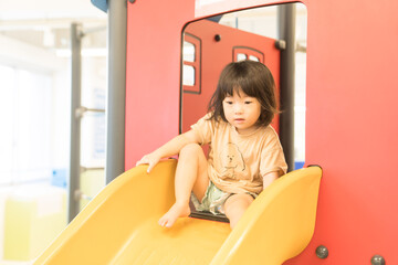 室内の滑り台で遊ぶ女の子の幼児