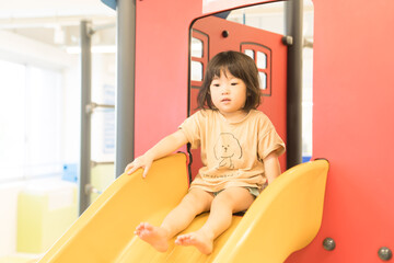 室内の滑り台で遊ぶ女の子の幼児