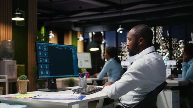Male PC user interacting with AI chat system on computer at office after hours, highlighting the evolution of artificial intelligence. Chatbot services and digital tools for productivity. Camera A.