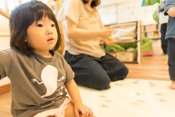 保育園で先生の話を聞く女の子の幼児