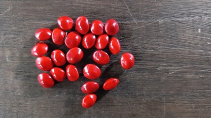 Close-up macro of glossy red saga tree seeds, tropical plant species Adenanthera pavonina.