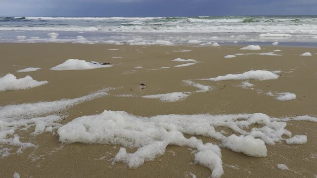 Foam pushed by waves towards Port Noarlunga Beach, signs of toxic bloom of Karenia mikimotoi, environmental catastrophe along St Vincent Gulf, Great Australian Bight, Fleurieu Peninsula, Adelaide
