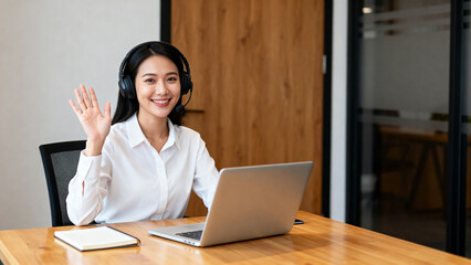 Woman wearing headphones waving at computer