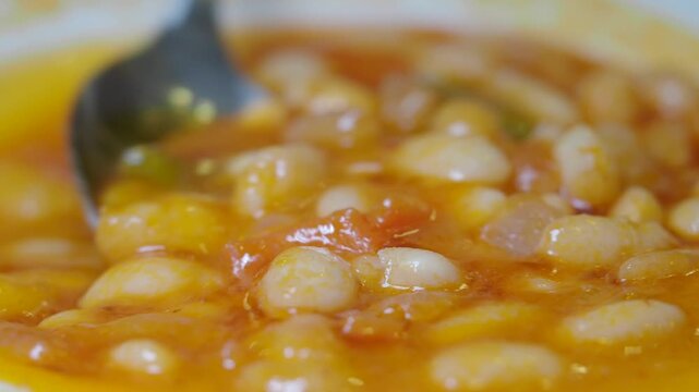 Delicious bean stew simmering in bright orange sauce