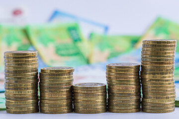 coins are neatly stacked in ascending order against blurred background vibrant banknotes. this scene represents financial growth and currency exchange, highlighting economic activities. close up.