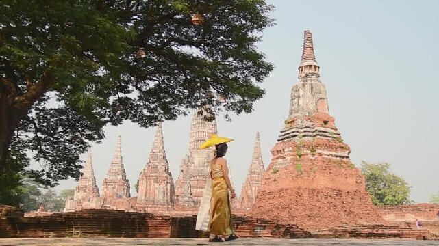 Thailand, Ayutthaya - march 15th, 2023: Woman in traditional Thai dress pose sightseeing visit ancient Buddha statue.Ayutthaya historical park. UNESCO World Heritage Site
