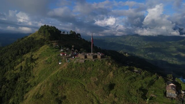 Aerial establishing shot of a hill station in Nepal with a large national flag, famous landmark for hikers and travelers, scenic nature background with mountain ranges