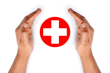 Hands covering a red medical cross icon on white background.