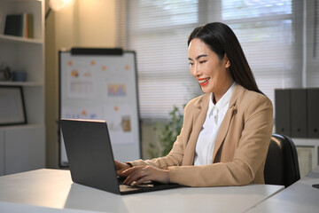 Professional businesswoman using laptop for business tasks or virtual meeting at workplace