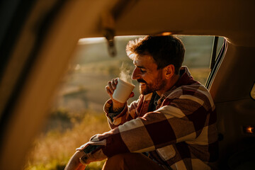 Man enjoying coffee during road trip at sunset