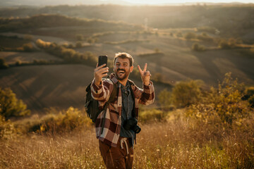 Man hiker taking selfie showing peace sign