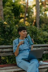 Medical professional relaxing with laptop and drink in park