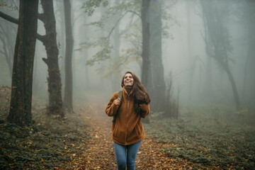 Woman hiking in foggy autumn forest enjoying nature