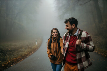 Couple hiking through a foggy autumn forest road